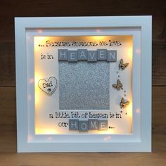 a frame with the words heaven and two butterflies on it, lit up by fairy lights