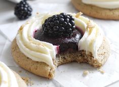 a cookie with white frosting and blackberries on top