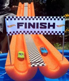 a little boy sitting on top of an inflatable pool with cars and checkered flags