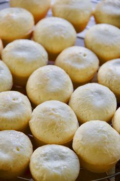 some food that is sitting on a wire rack in front of a plate full of muffins