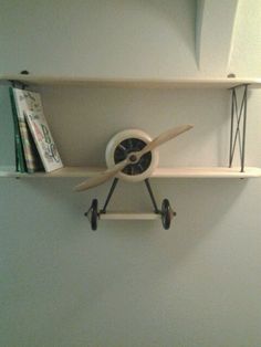 a wall shelf with some books and a clock on it