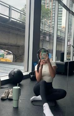 a woman sitting on the floor taking a selfie with her cell phone and headphones