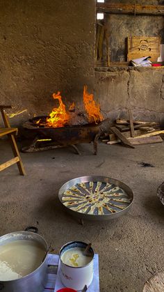 a fire burns in an old building with pots and pans sitting on the floor