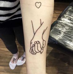 two hands holding each other with a heart tattoo on their wrist and the word love written in black ink