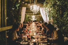 a group of people sitting at a long table with food and drinks in front of them