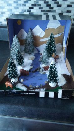 an open cardboard box with trees and animals in the snow on it's side