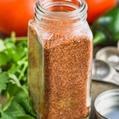 a jar filled with seasoning next to spoons and tomatoes