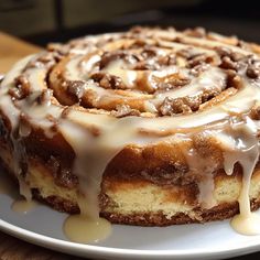 a cinnamon roll cake on a plate with icing drizzled around it