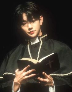 a young man wearing a priest's robe and holding a book in his hands