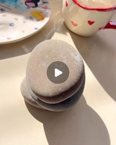 two rocks sitting on top of a table next to a cup and saucer with a spoon