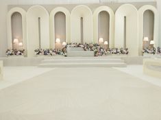 a large room with white walls and flooring, decorated with floral arrangements on the wall