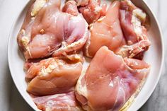 raw chicken pieces in a white bowl on a table