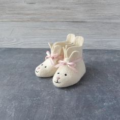 a pair of white slippers with pink bows on the toes and ears are sitting on a gray surface