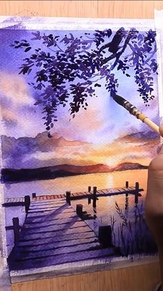 someone is painting a sunset scene with watercolors