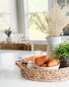 a basket filled with vegetables sitting on top of a table next to a vase full of flowers