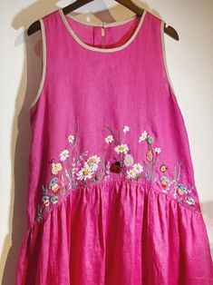 a pink dress with flowers on it hanging from a hanger