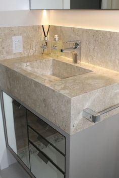 a bathroom sink sitting under a mirror next to a counter top with lights on it