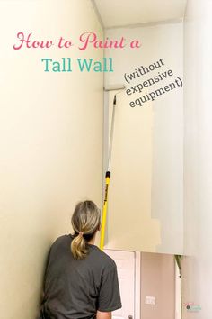 a woman is painting the wall with white paint