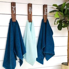 three blue towels hanging on the wall next to a potted plant