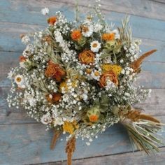 a bouquet of flowers sitting on top of a wooden table next to a blue wall