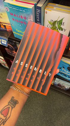 a person holding up a book in front of bookshelves