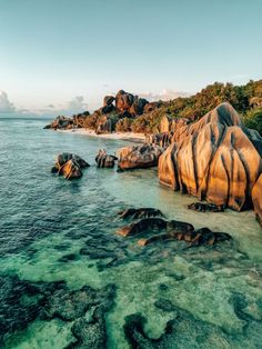 an aerial view of the ocean with rocks in the foreground and clear blue water