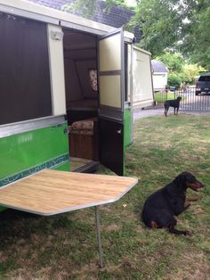 a dog sitting in the grass next to a trailer