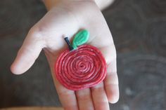 a child's hand holding a piece of yarn with a green leaf on it