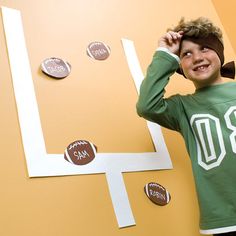 a young boy standing in front of a wall with paper cutouts and magnets on it