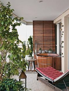 a hot tub sitting on top of a wooden floor next to a lush green tree