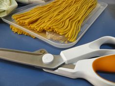 a pair of scissors sitting on top of a blue table next to some yellow yarn