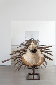 a sculpture made out of wood sticks in a room with white walls and flooring