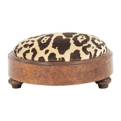 an animal print footstool with wooden legs and a cushion on the top, in front of a white background