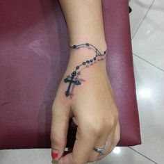 a woman's hand with a rosary tattoo on it