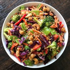 a salad with broccoli, carrots and cashews in a white bowl