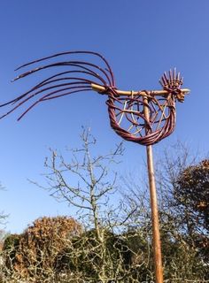 a sculpture made out of branches in the shape of a bird's head on top of a pole