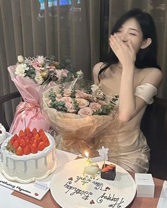 a woman sitting at a table in front of a cake with strawberries on it