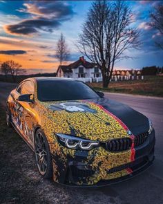 a yellow and black car parked on the side of a road with trees in the background