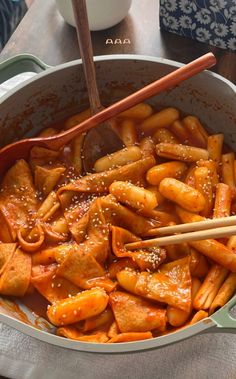 a pan filled with pasta and chopsticks on top of a table