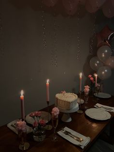 a table topped with a cake covered in frosting next to candles and plates filled with food