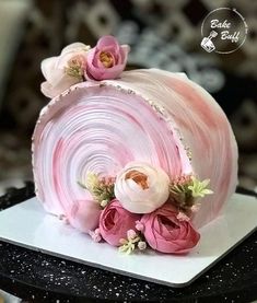 there is a pink cake with flowers on the top and sides, sitting on a white plate