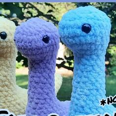 three different colored crocheted birds sitting next to each other in front of trees