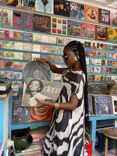 a woman standing in front of a record store with records on the wall behind her