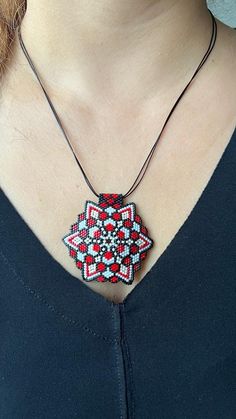 a woman wearing a red and white beaded necklace with a flower design on it