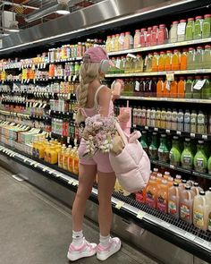 a woman is standing in front of a display of juices