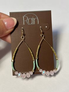 a pair of pink and green beaded hoop earrings on top of a brown card