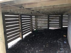 the inside of an enclosed area with wood slats and black mulch on the ground