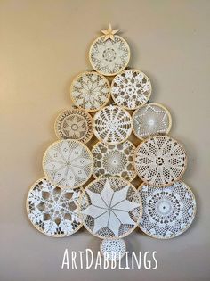 a christmas tree made out of doily and wooden slices is hanging on the wall