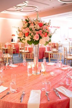 a vase filled with flowers sitting on top of a table covered in white and pink linens