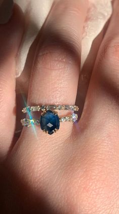 a woman's hand with a ring on it and a blue stone in the middle